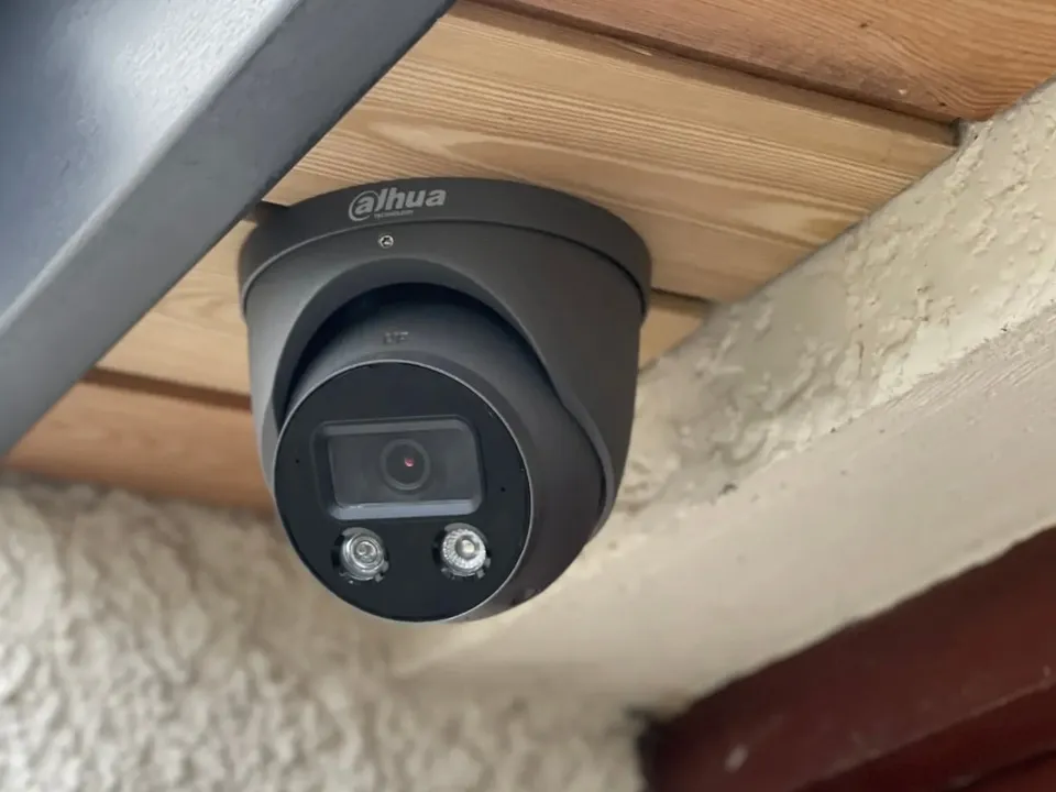 Close-up of a dark grey turret camera under a timber-lined eave