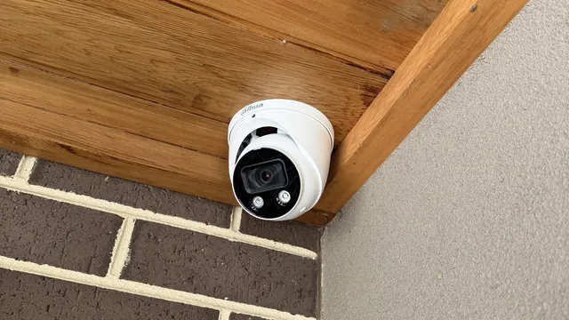 White turret camera under the timber-lined eave of a brick home