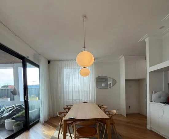 Pendant feature lights hanging over a dining table in a bright open-plan room
