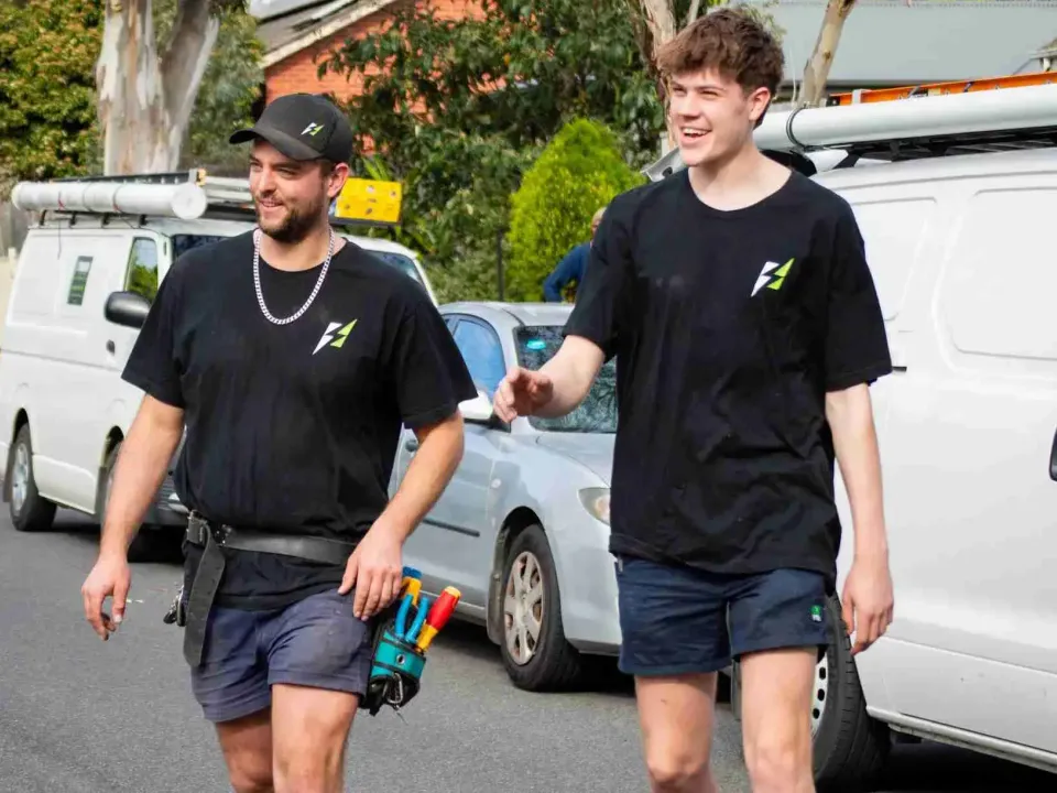 Two Streamline electricians walking from their vans on a residential street