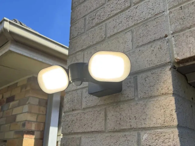 Electrician installing a sensor security light on the outside of a house