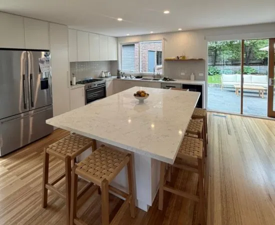 Bright kitchen with downlights over a stone island bench