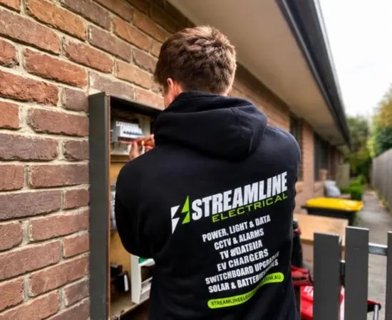 Streamline electrician inspecting an outdoor meter box on a brick wall