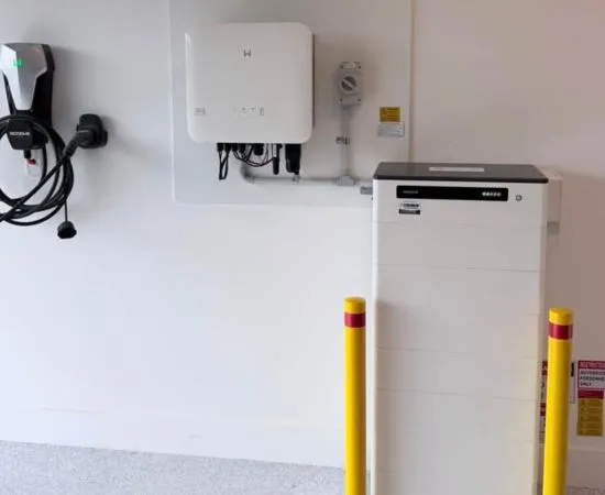 Wall-mounted EV charger, inverter and battery installed in a garage with protective bollards